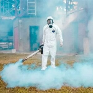 فني شركة قوة الطبيعة بزي الوقاية الكاملة أثناء تنفيذ عملية مكافحة حشرات غرب الرياض باستخدام تقنية الضباب الحراري.