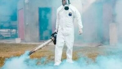 فني شركة قوة الطبيعة بزي الوقاية الكاملة أثناء تنفيذ عملية مكافحة حشرات غرب الرياض باستخدام تقنية الضباب الحراري.